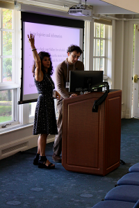 Dorit Bar-On and Utku Sonsayar stand at a podium in front of a PowerPoint slide, addressing attendees of the ELM2 Conference.